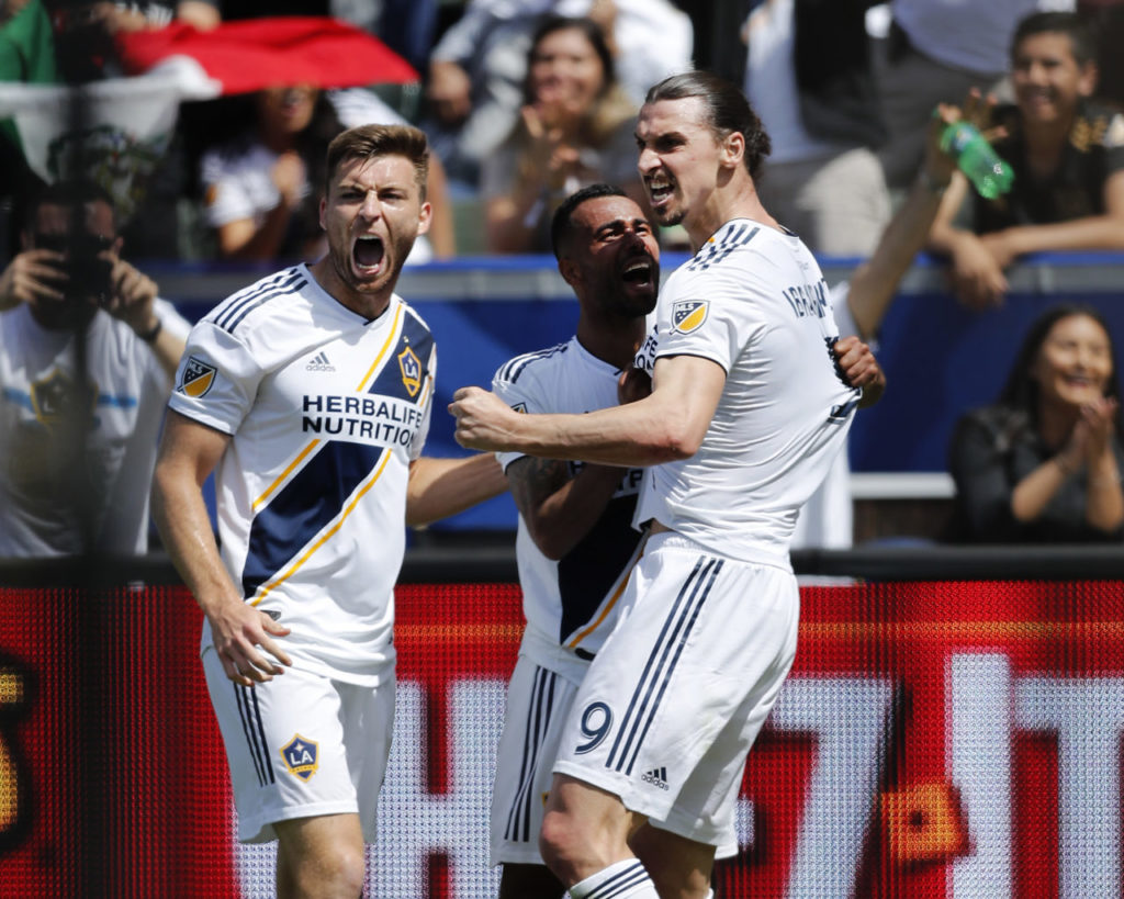epa06639658 Los Angeles Galaxy David Romney (L) and Ashley Cole (C) celebrate with new teammate Zlatan Ibrahimovic of Sweden (R) after Ibrahimovic's second goal in the second half against Los Angeles Football Club at StubHub Center in Carson, California, USA 31 March 2018. Ibrahimovic made two goals including the game-winner in his Los Angeles Galaxy debut. EPA-EFE/PAUL BUCK