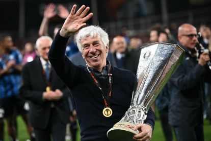 Atalanta's Italian coach Gian Piero Gasperini smiles, holding the trophy as Atalanta's players celebrate after the UEFA Europa League final football match between Atalanta and Bayer Leverkusen at the Dublin Arena stadium, in Dublin, on May 22, 2024. Atalanta won the game 3-0. (Photo by Paul ELLIS / AFP) (Photo by PAUL ELLIS/AFP via Getty Images)