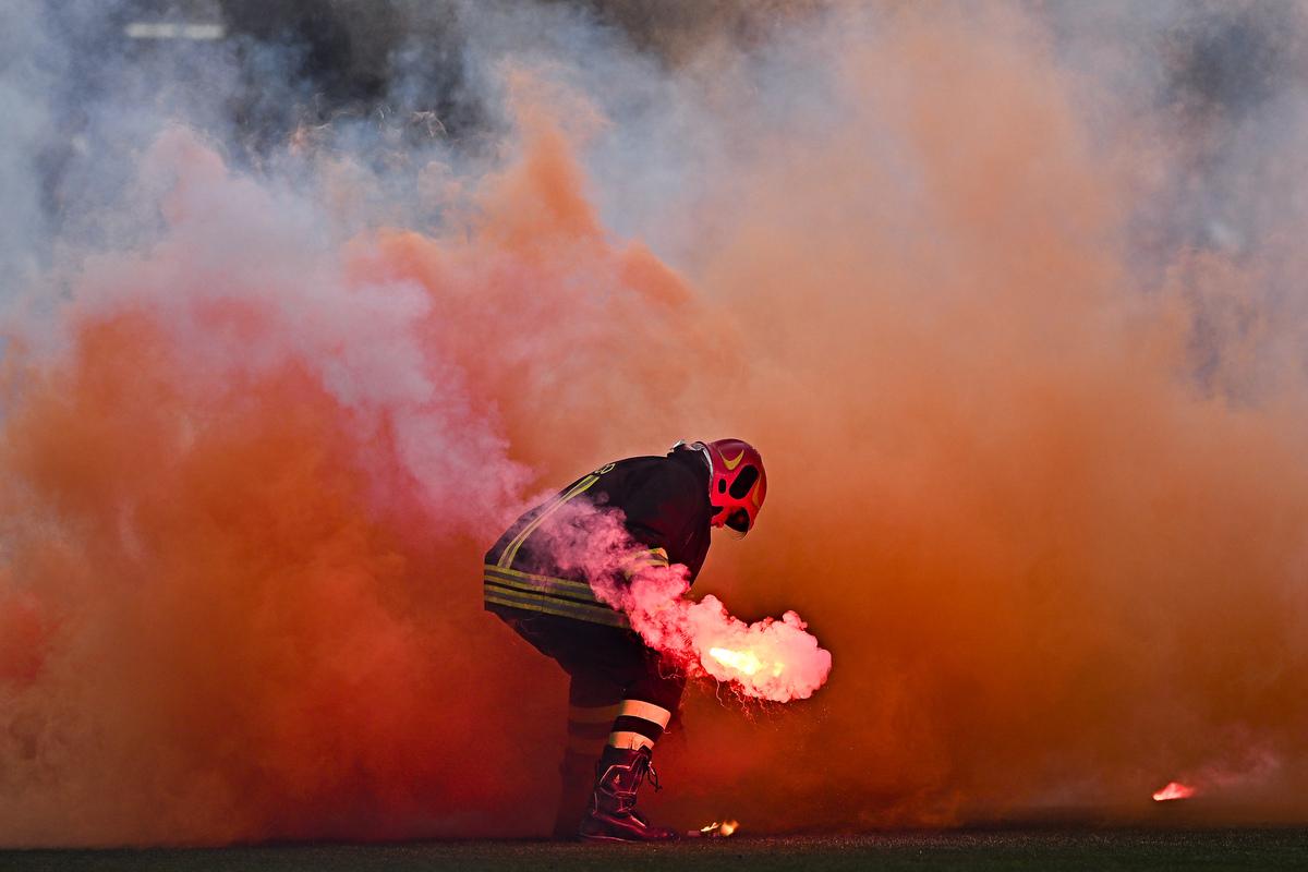 GENOA, ITALY - APRIL 23: A fireman is seen at work as flares and smoke-bombs are thrown onto the pitch by Genoa fans during the Serie A match between Genoa and SS Lazio at Stadio Luigi Ferraris on April 23, 2025 in Genoa, Italy. (Photo by Simone Arveda/Getty Images)