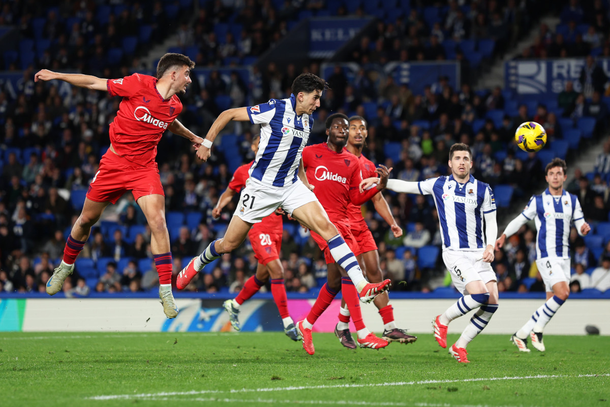 SAN SEBASTIAN, SPAIN - MARCH 09: Nayef Aguerd of Real Sociedad heads the ball at goal whilst under pressure from Kike Salas of Sevilla FC during the LaLiga match between Real Sociedad and Sevilla FC at Reale Arena on March 09, 2025 in San Sebastian, Spain. (Photo by Ion Alcoba Beitia/Getty Images)