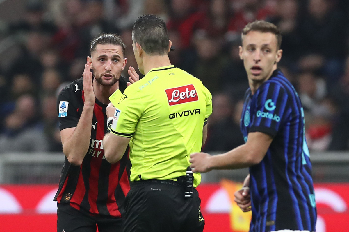 MILAN, ITALY - MARCH 08: Referee Daniele Doveri shows the yellow card to Adrien Rabiot of AC Milan during the Serie A match between AC Milan and Inter at Giuseppe Meazza Stadium on March 08, 2026 in Milan, Italy. (Photo by Marco Luzzani/Getty Images)