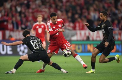 MUNICH, GERMANY - MAY 06: Jamal Musiala of FC Bayern Munich runs with the ball while under pressure from Joao Neves and Bradley Barcola of Paris Saint-Germain during the UEFA Champions League 2025/26 Semi Final Second Leg match between FC Bayern München and Paris Saint-Germain at Football Arena Munich on May 06, 2026 in Munich, Germany. (Photo by Alex Grimm/Getty Images)