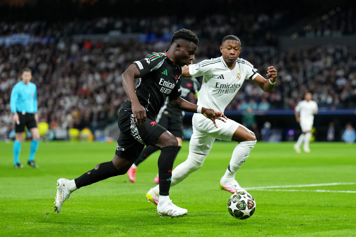 MADRID, SPAIN - APRIL 16: Bukayo Saka of Arsenal runs with the ball whilst under pressure from David Alaba of Real Madrid during the UEFA Champions League 2024/25 Quarter Final Second Leg match between Real Madrid C.F. and Arsenal FC at Estadio Santiago Bernabeu on April 16, 2025 in Madrid, Spain. (Photo by Angel Martinez/Getty Images)